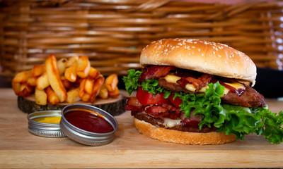 Deliciosa hamburguesa casera fresca con lechuga, queso, cebolla y tomate sobre una tabla de madera rústica con fondo de mimbre