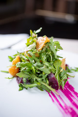 A view of a stylized beet salad with arugula, in a restaurant or kitchen setting.