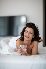 Obraz na płótnie Canvas Beautiful young woman drinking water in bed on a lovely morning