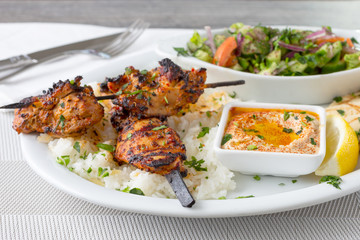 A view of a plate of chicken shish kabobs, in a restaurant or kitchen setting.