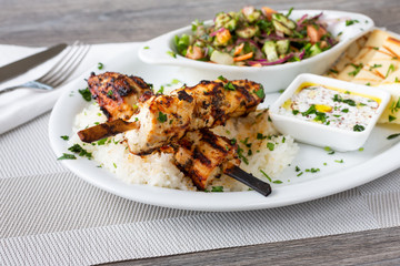 A view of a plate of chicken shish kabobs, in a restaurant or kitchen setting.
