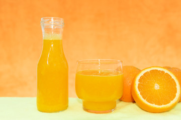 Fototapeta na wymiar Un bote y un vaso con zumo de naranja recién exprimido