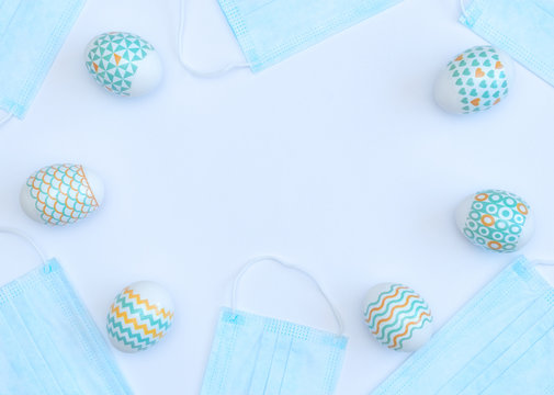 Decorated Easter eggs with medical face masks on white background with copy space. Happy Easter during quarantine concept. Biohazard, 2019-nCoV, COVID-19, social distance, stay home. Flat lay.