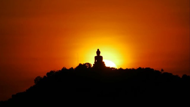 Timelapse hue sunset over and behind silhouette Phuket big buddha statue on hilltop, tree high mountain, with beauty colorful twilight sky background, tourist photo spot attraction