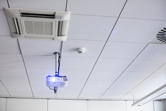 A white overhead projector on ceiling in a conference room/modern classroom (color toned image)