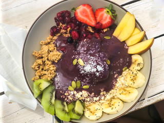 Trendy summer açai breakfast: vitamin-rich bowls with strawberries, bananas, blueberries, kiwi, and granola