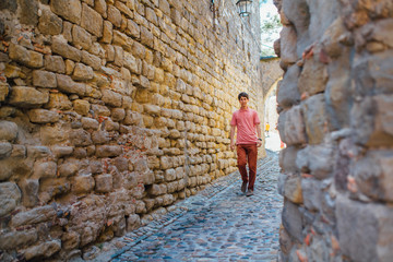 A young man stands against a wall on a street in the medieval city of Carcassonne in France