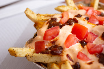 A closeup view of a tray of loaded fries, in a restaurant or kitchen setting.