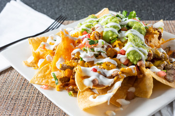 A view of a plate of carne asada nachos, in a restaurant or kitchen setting.