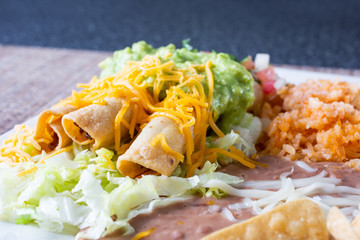 A view of a taquitos plate, in restaurant or kitchen setting.