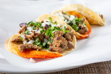 A closeup view of several street tacos, in a restaurant or kitchen setting.