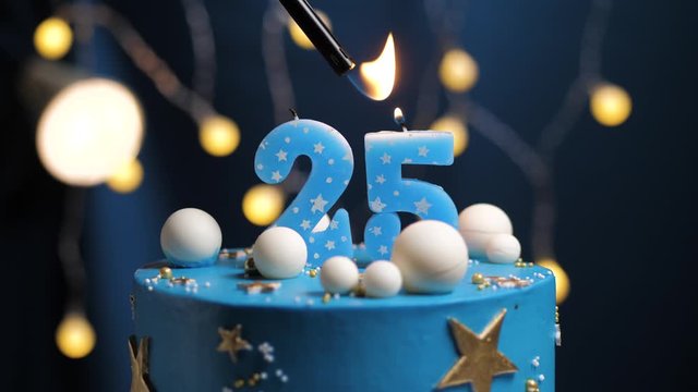 Birthday cake number 25 stars sky and moon concept, blue candle is fire by lighter and then blows out. Copy space on right side of screen if required. Close-up and slow motion