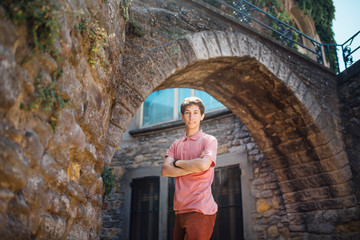 A young man stands against a wall on a street in the medieval city of Carcassonne in France