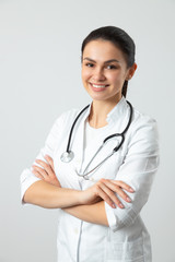 Cute smiling doctor posing for camera against light background