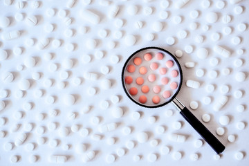 Concept of health care, medicine, pharmacy, COVID-19, coronavirus. Treatment and prevention of diseases. Assortment of medicinal pharmaceutical products, white and pink pills with a magnifying glass.