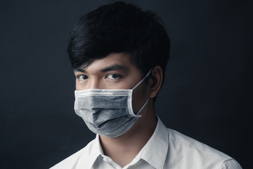 Asian man with medical mask on his face in black background - Studio portrait