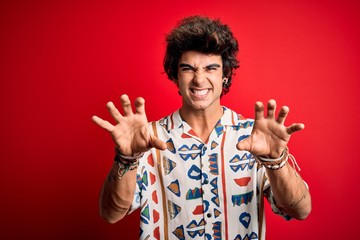 Young handsome man on vacation wearing summer shirt over isolated red background smiling funny...