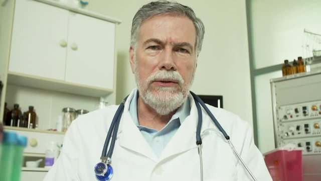 A mature bearded physician engaged in a video conference with someone on the other end of this virtual doctor visit.