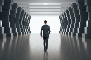 Fototapeta premium Businessman walking in minimalistic concrete tunnel interior.