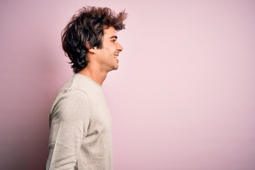 Young handsome man wearing casual t-shirt standing over isolated pink background looking to side, relax profile pose with natural face and confident smile.