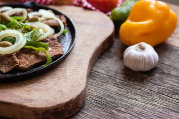 Fried meat on iron plate with rustic wooden background