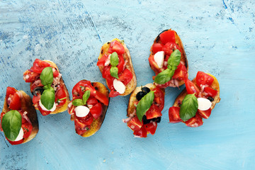 Traditional italian bruschetta with cherry tomatoes, cream cheese, basil leaves on rustic background. Italian antipasti mediterranean food