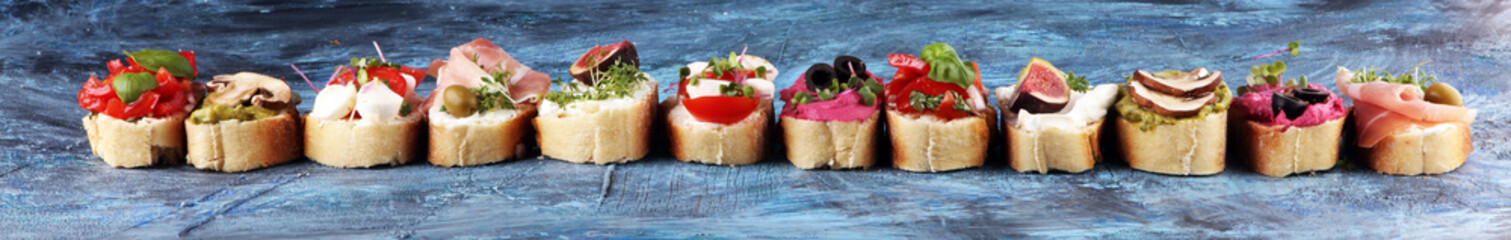 Assorted bruschetta with various toppings. Appetizing bruschetta or crudo crostini. Variety of small sandwiches. Mix bruschetta with tomatoes and basil