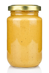 Mustard in a transparent glass jar with a closed gilded metal lid isolated on white background
