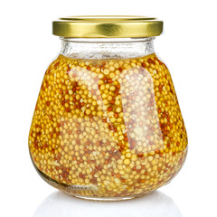French mustard in a pyramid transparent glass jar with a closed gilded metal lid isolated on white background