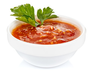 Hot tomato sauce with parsley leaves in a small white ceramic round bowl isolated on white background