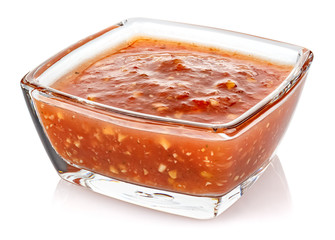 Hot tomato sauce with spices and salt in a small transparent glass square bowl isolated on white background