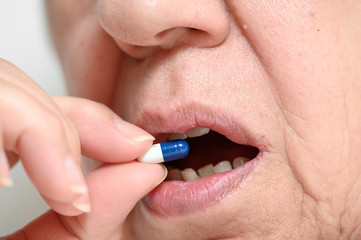 Close up of a senior woman swallowing pill . 