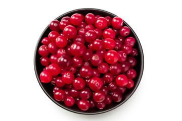 Cranberry in a black plate with green leaves isolated on white background. top view
