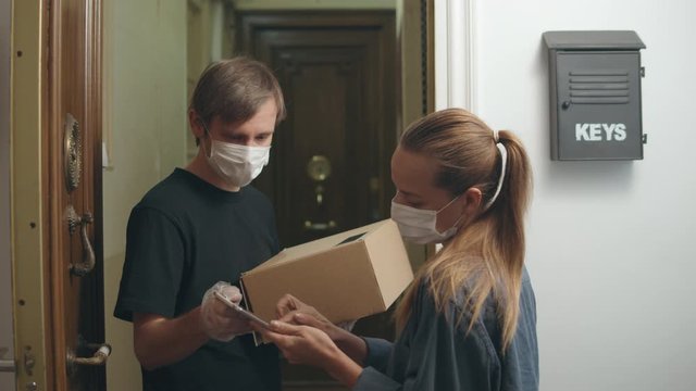 postman or delivery man carry small box deliver to young woman customer at home. Man wearing mask prevent covid or coranavirus quarantine pandemic. Social distancing home isolation work concept.