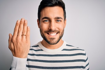Handsome man with beard showing alliance ring marriage on finger over white background with a happy...