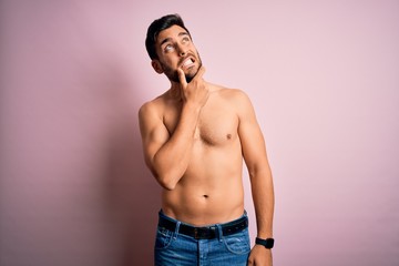 Fototapeta premium Young handsome strong man with beard shirtless standing over isolated pink background Thinking worried about a question, concerned and nervous with hand on chin
