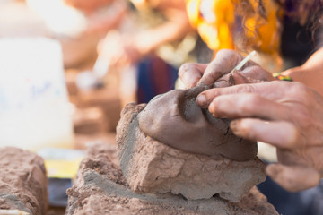 Hands of a person making a clay sculpture.