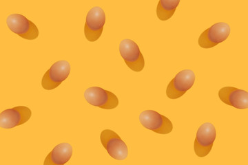 Modern minimalistic easter pattern. Brown eggs on yellow background.