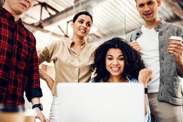 Cheerful business colleagues using laptop at work