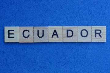 gray word ecuador from small wooden letters on a blue table