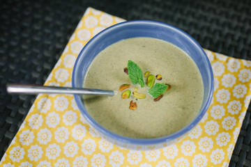 Pistachio cold soup garnished with mint in a blue bowl