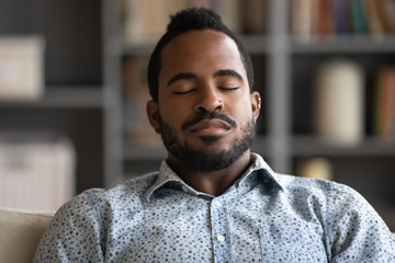 Close up of calm African American young man rest at home daydream or take nap feeling fatigue, exhausted biracial millennial male fall asleep relax in living room, sleeping or taking break - Powered by Adobe