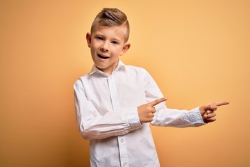 Young little caucasian kid with blue eyes wearing elegant white shirt over yellow background...