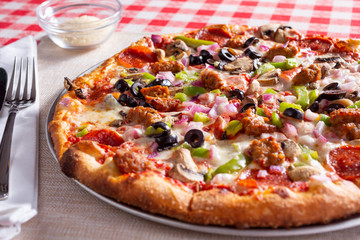 A view of a meat and veggie pizza pie, in a restaurant or kitchen setting.