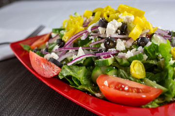 A view of a Greek style garden salad, in a restaurant or kitchen setting.