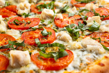 A closeup view of the texture of a Margherita and chicken pizza pie, as a background.