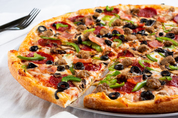 A view of a deluxe style pizza pie, in a restaurant or kitchen setting.