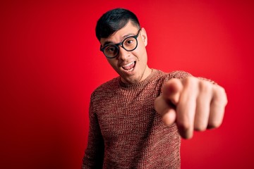 Young handsome hispanic man wearing nerd glasses over red background pointing displeased and...
