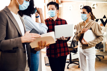 Office workers in medical face masks working on project - Powered by Adobe