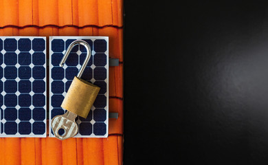 Padlock with key on photovoltaic solar panel on black background